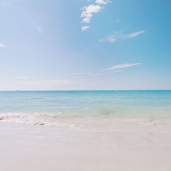 Voyage en Asie — Plage de Pantai Pasir Putih à Bali avec son sable blanc et ses eaux turquoise bordées de végétation tropicale.