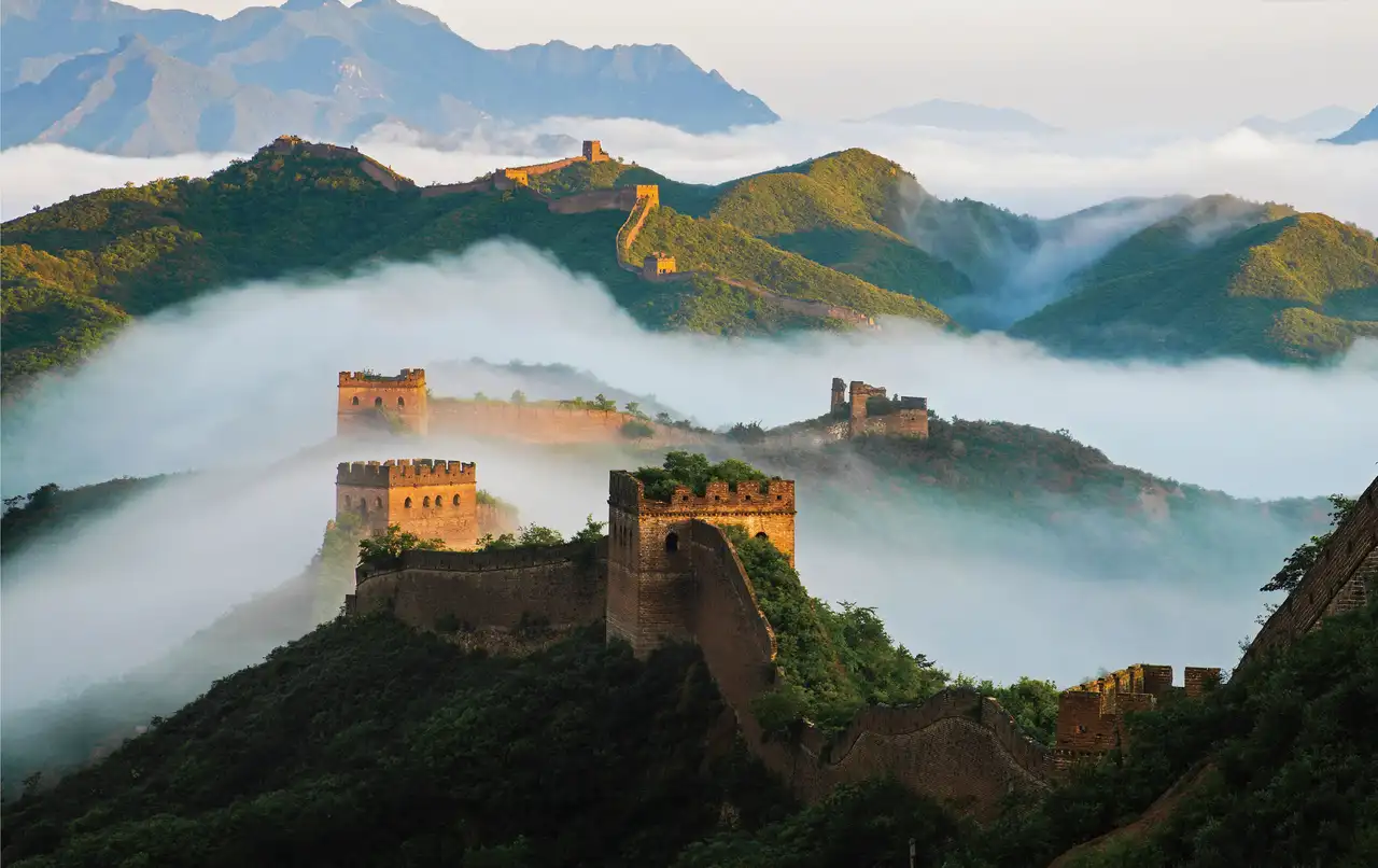 Vue de la Grande Muraille de Chine et de ses tours de guet serpentant à travers les montagnes entourées d'une mer de nuages.