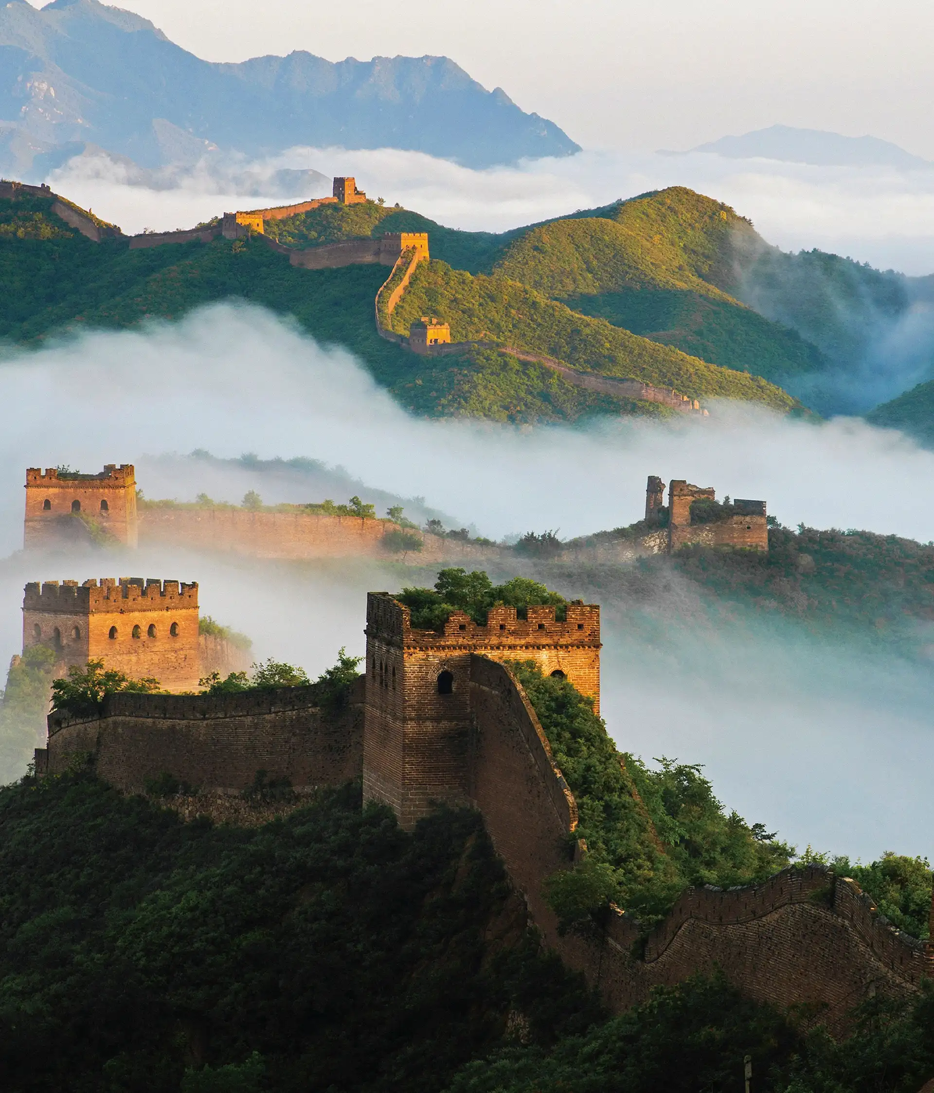 Vue de la Grande Muraille de Chine et de ses tours de guet serpentant à travers les montagnes entourées d'une mer de nuages.