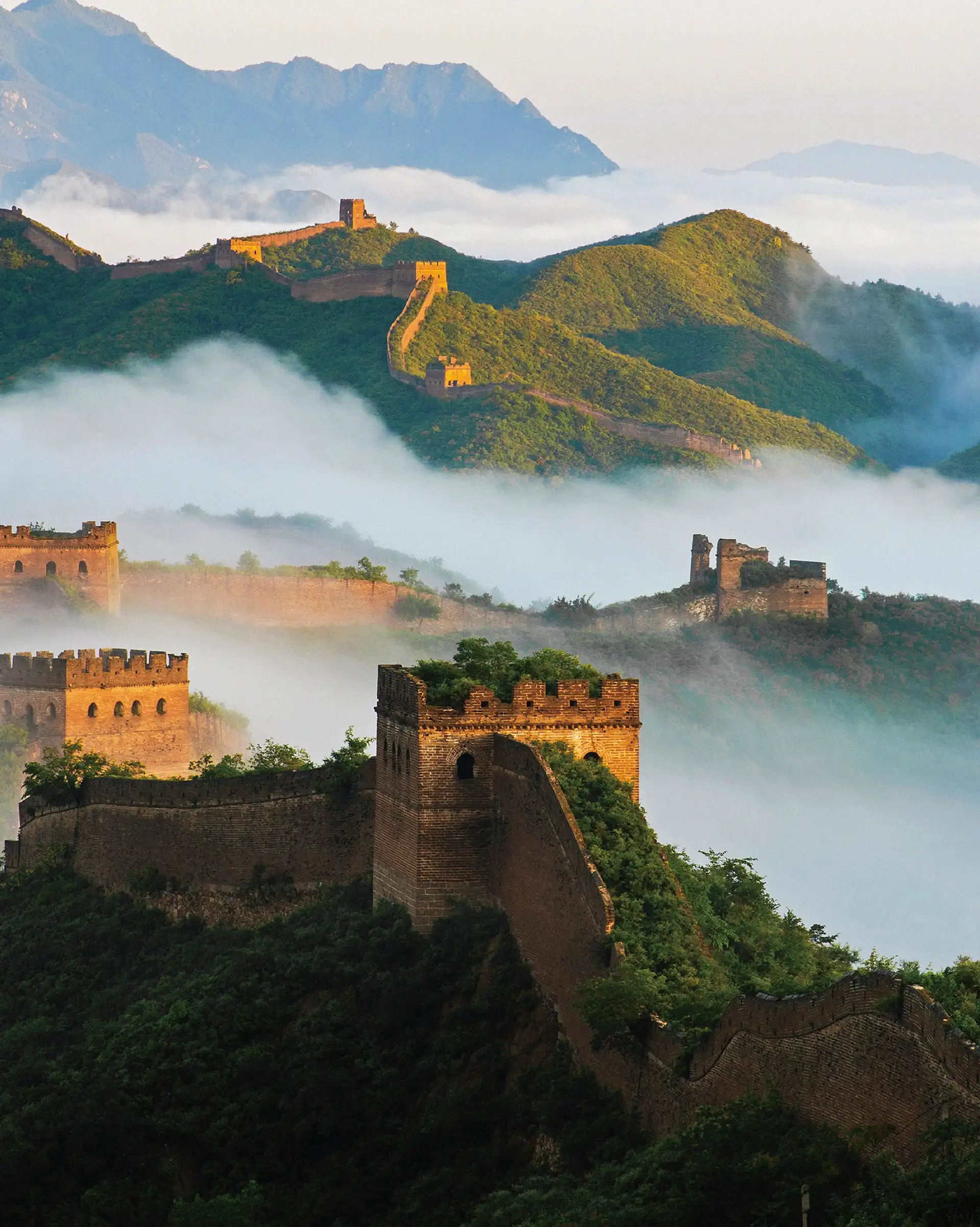Vue de la Grande Muraille de Chine et de ses tours de guet serpentant à travers les montagnes entourées d'une mer de nuages.