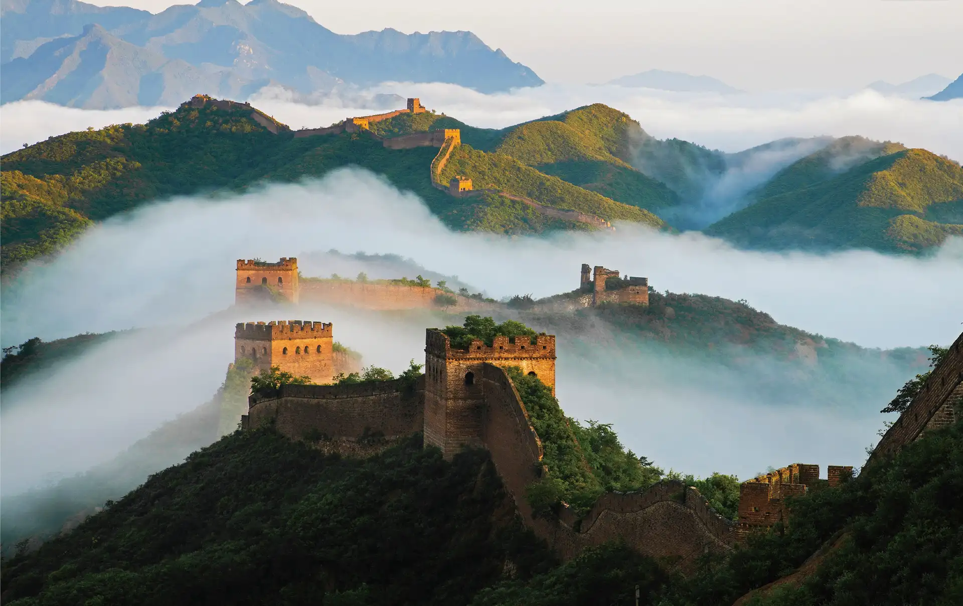 Vue de la Grande Muraille de Chine et de ses tours de guet serpentant à travers les montagnes entourées d'une mer de nuages.