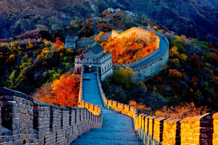 La Grande Muraille de Chine illuminée au crépuscule serpentant à travers les montagnes aux couleurs d'automne à Badaling.