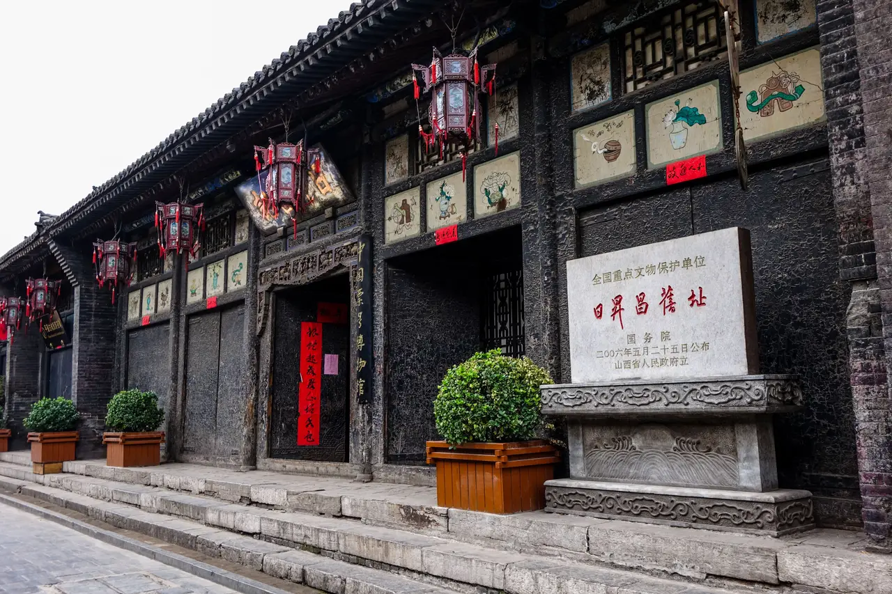 Façade traditionnelle en pierre et bois ornée de lanternes rouges de l'ancienne banque Rishengchang dans la cité fortifiée de Pingyao.