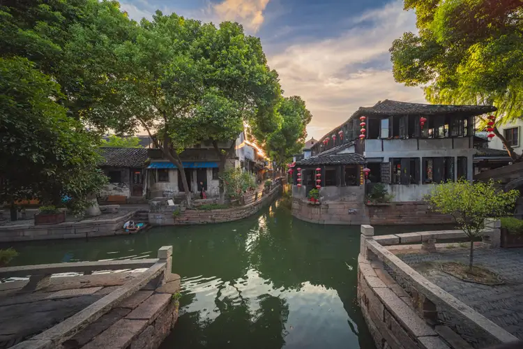 Canal paisible bordé de maisons traditionnelles chinoises et de végétation luxuriante dans un village d'eau près de Suzhou.