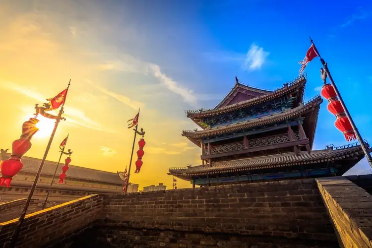 Tour de garde traditionnelle chinoise et lanternes rouges bordant les anciens remparts de Xi'an au coucher du soleil.