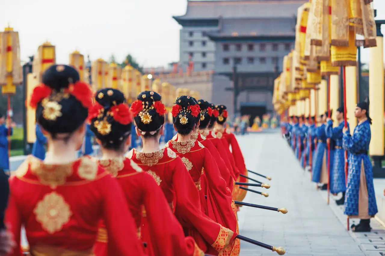 Procession d'hommes et de femmes vêtus de costumes traditionnels Hanfu lors d'une cérémonie d'accueil historique sur les remparts de Xi'an.