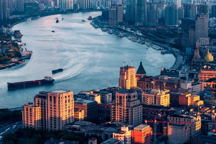 Vue aérienne du Bund à Shanghai bordant le fleuve Huangpu avec ses bâtiments historiques à l'architecture coloniale au crépuscule.