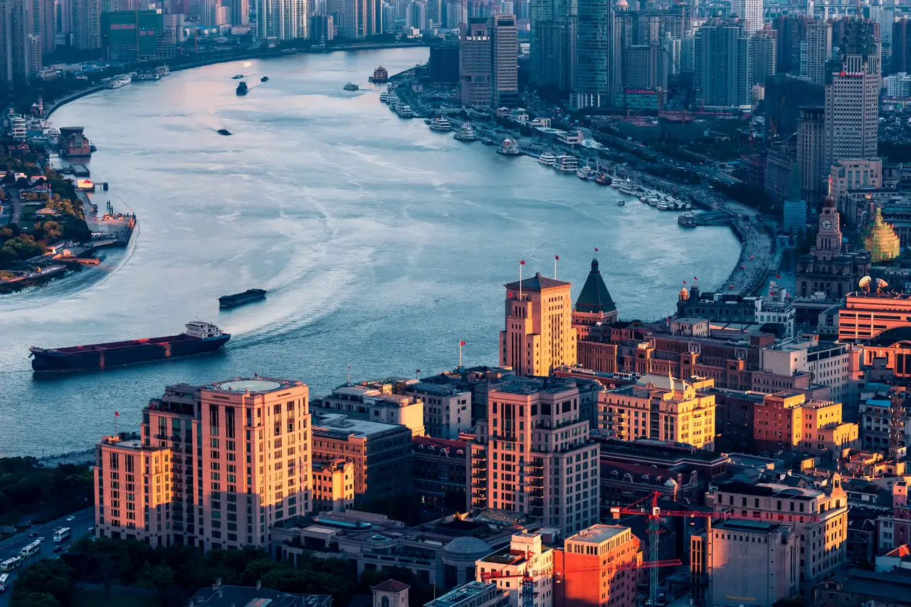 Vue aérienne du Bund à Shanghai bordant le fleuve Huangpu avec ses bâtiments historiques à l'architecture coloniale au crépuscule.