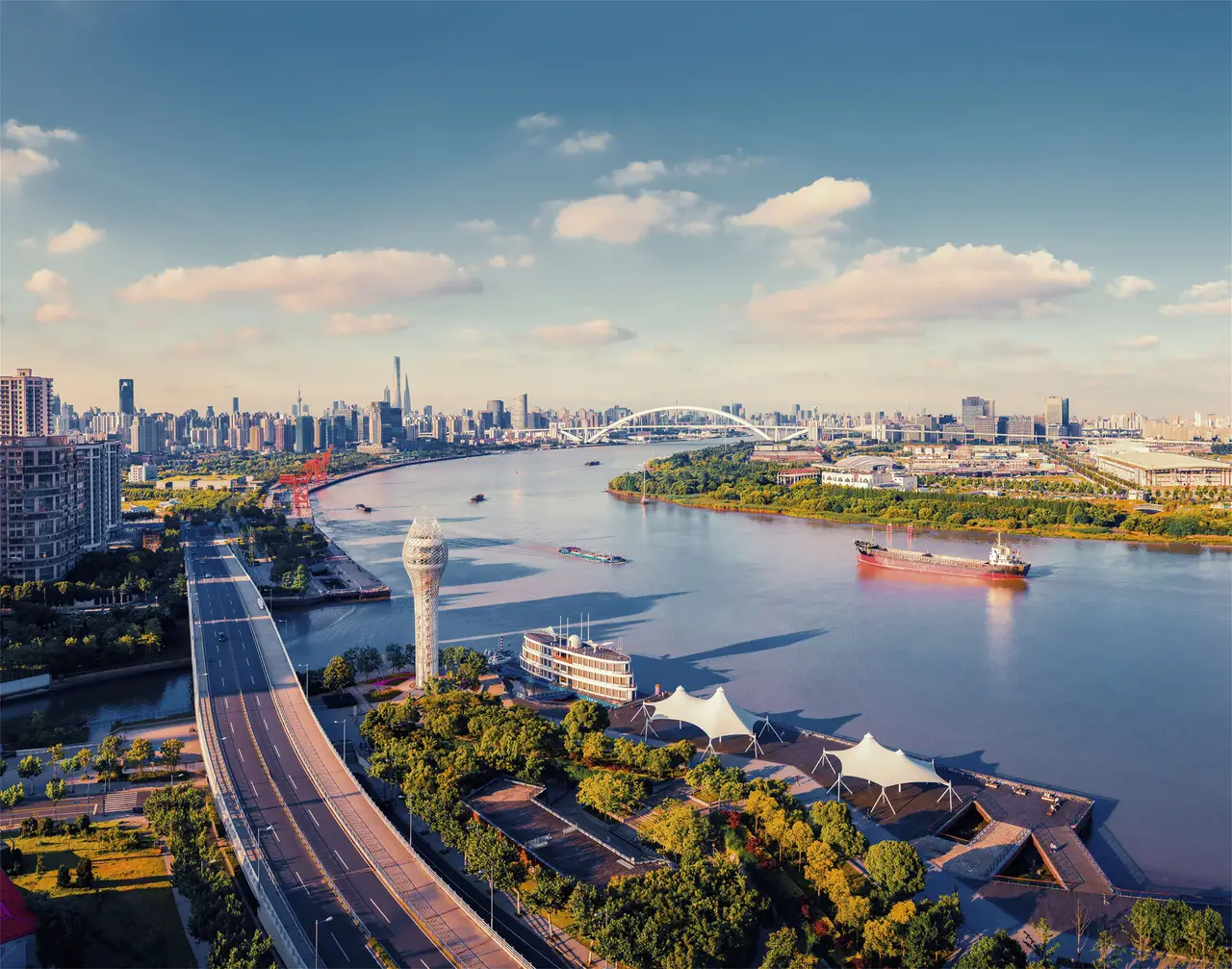 Vue aérienne du quartier moderne de Xuhui Riverside bordant le fleuve Huangpu avec la skyline de Shanghai en arrière-plan.