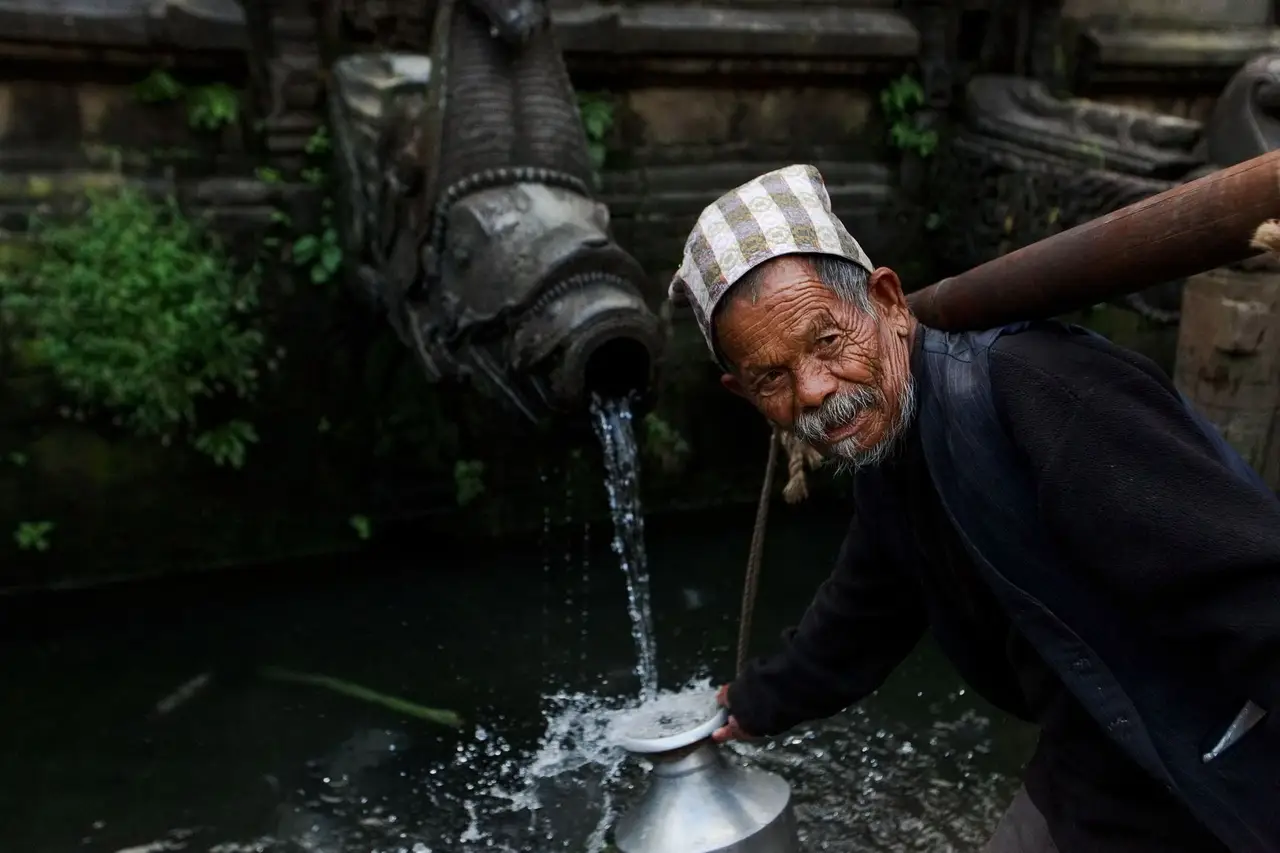 un homme a coté d'un bassin sacré au népal