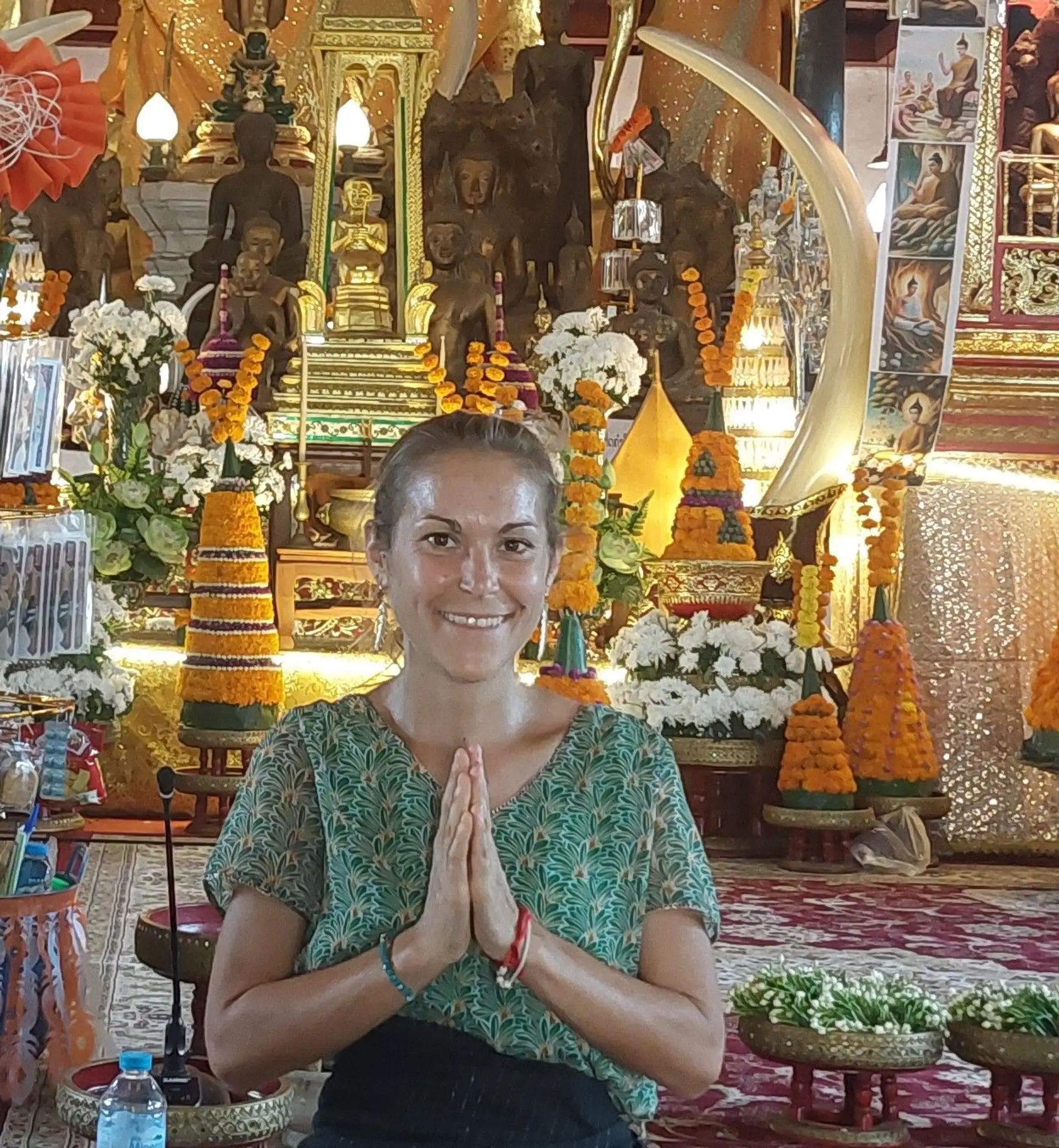 Portrait de Doriane, experte voyage chez Shanti Travel, faisant le geste du salut traditionnel devant un temple.