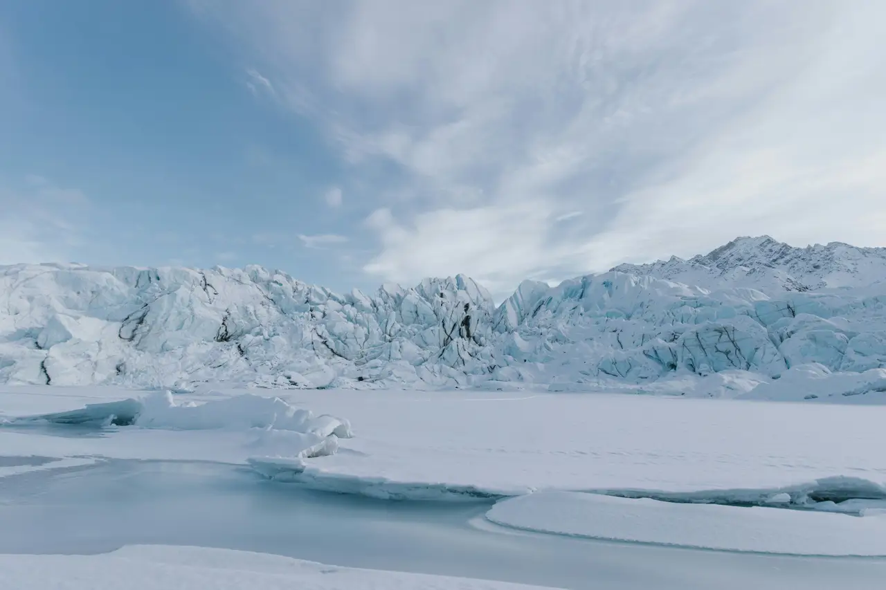 Front de glacier avec blocs de glace bleutée et reflets d'eau sous un ciel lumineux à Valdez en Alaska
