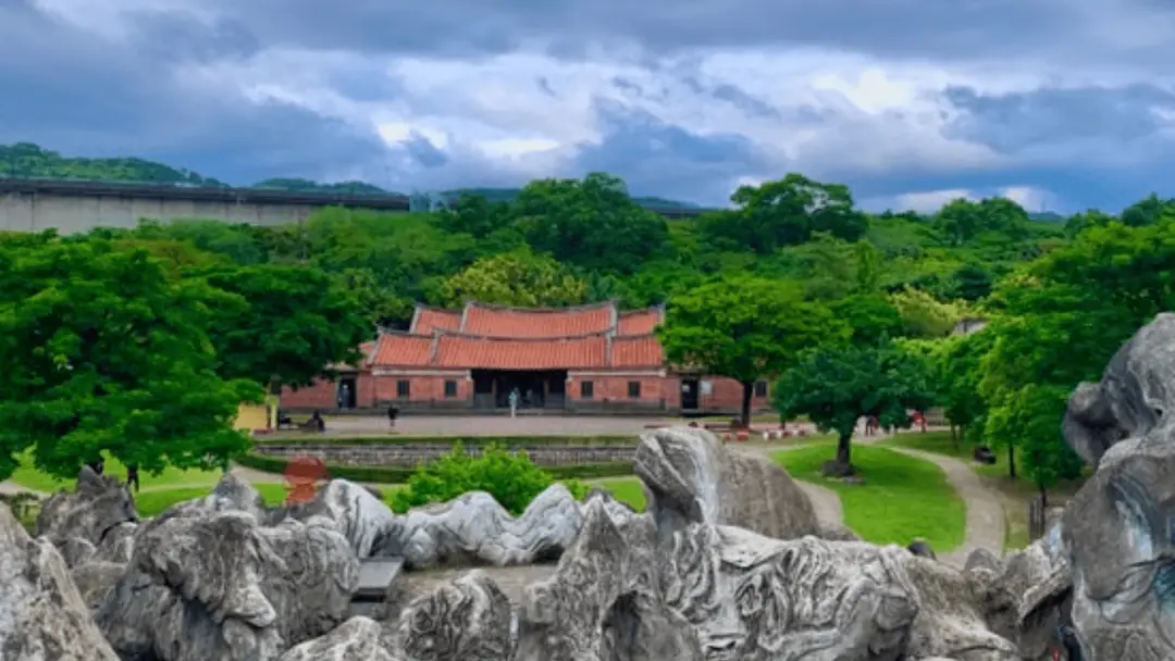 temple historique niché dans une verdure luxuriante et des rochers sous un ciel dramatique à Taipei..png