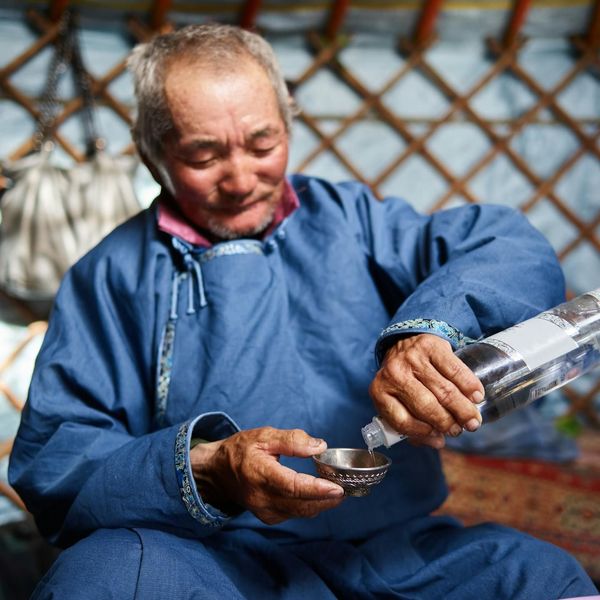 Un homme mongol versant une liqueur dans un bol traditionnel