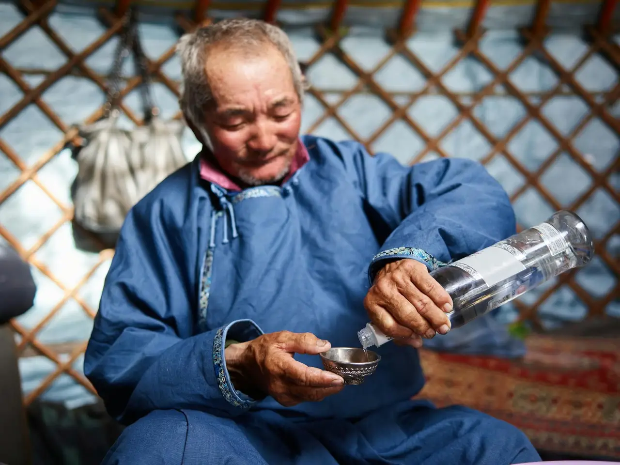 Un homme mongol versant une liqueur dans un bol traditionnel