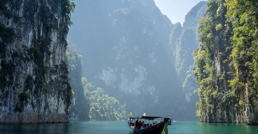 Voyage en Asie — Bateau traditionnel naviguant dans la baie de Phang Nga en Thaïlande, paysage karstique et nature tropicale