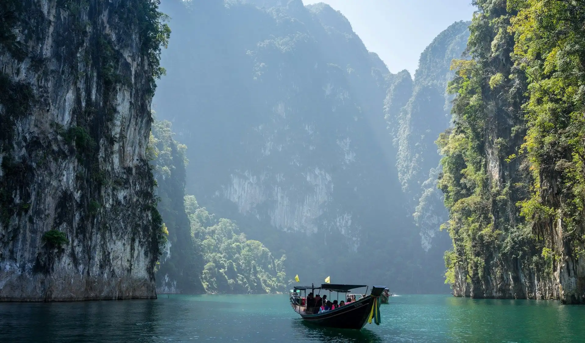 Immenses falaises de calcaire karstique recouvertes de végétation tropicale se dressant au-dessus des eaux émeraude en Thaïlande.