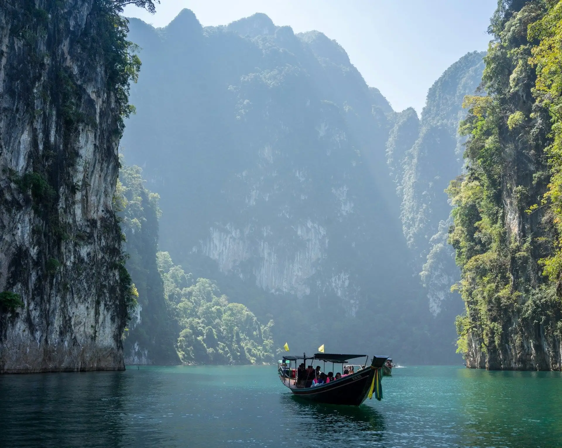 Voyage en Asie — Bateau traditionnel naviguant dans la baie de Phang Nga en Thaïlande, paysage karstique et nature tropicale