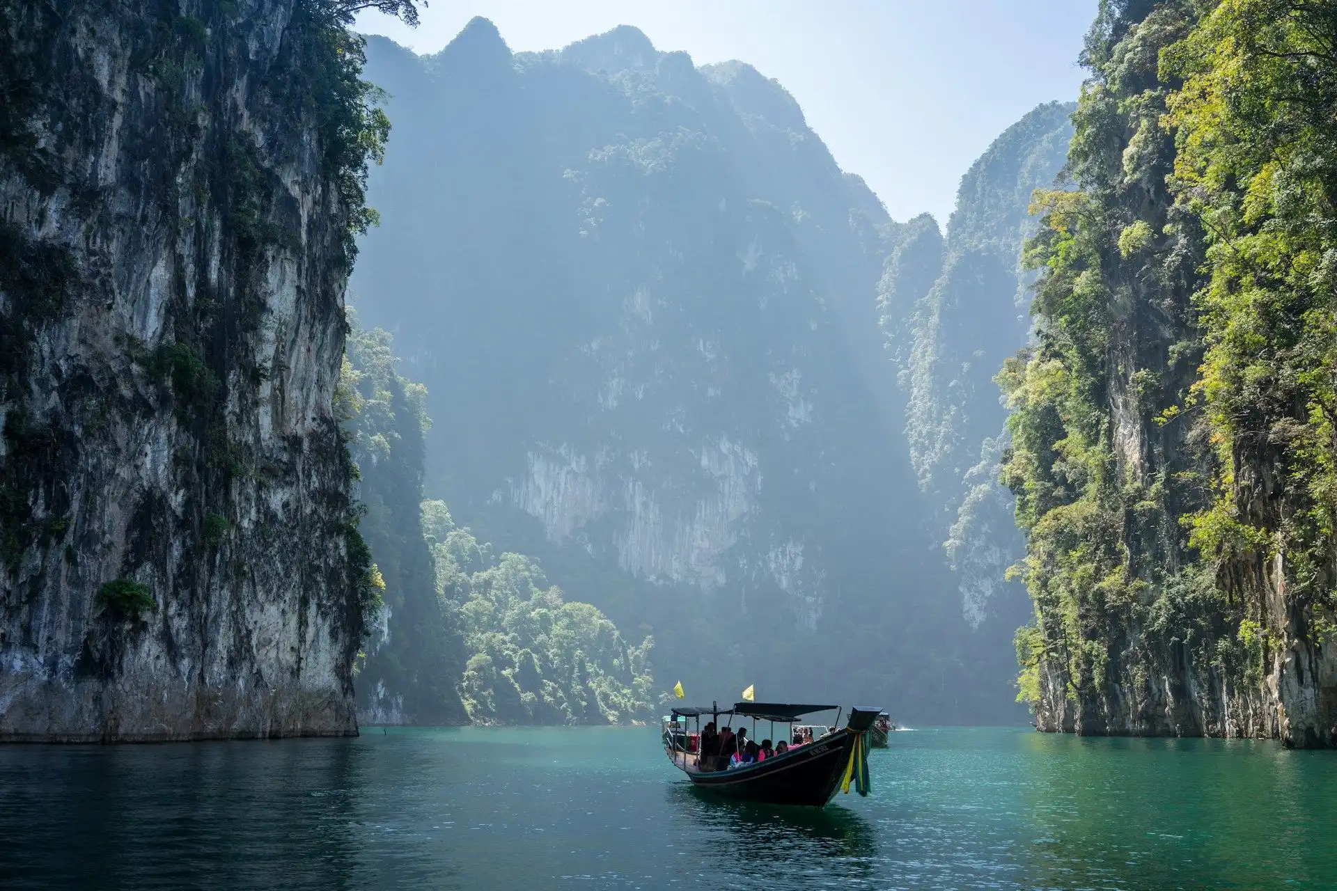 Immenses falaises de calcaire karstique recouvertes de végétation tropicale se dressant au-dessus des eaux émeraude en Thaïlande.
