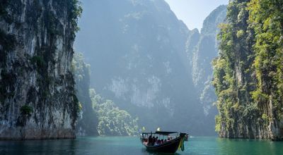 Voyage en Asie — Bateau traditionnel naviguant dans la baie de Phang Nga en Thaïlande, paysage karstique et nature tropicale