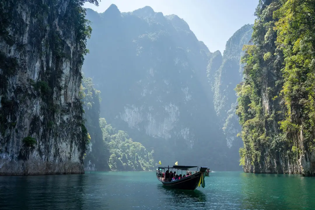 Immenses falaises de calcaire karstique recouvertes de végétation tropicale se dressant au-dessus des eaux émeraude en Thaïlande.