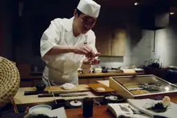 Chef japonais préparant avec précision un sushi traditionnel dans le quartier du marché de Tsukiji à Tokyo.