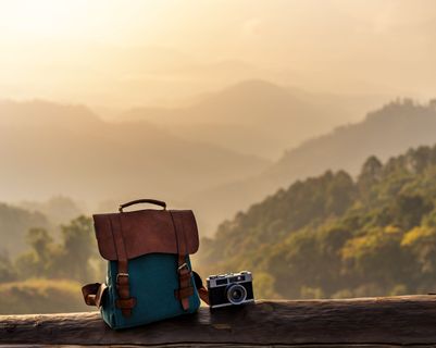 Voyage en Asie – Sac à dos et appareil photo devant un paysage montagneux, évoquant liberté et introspection du voyage solo