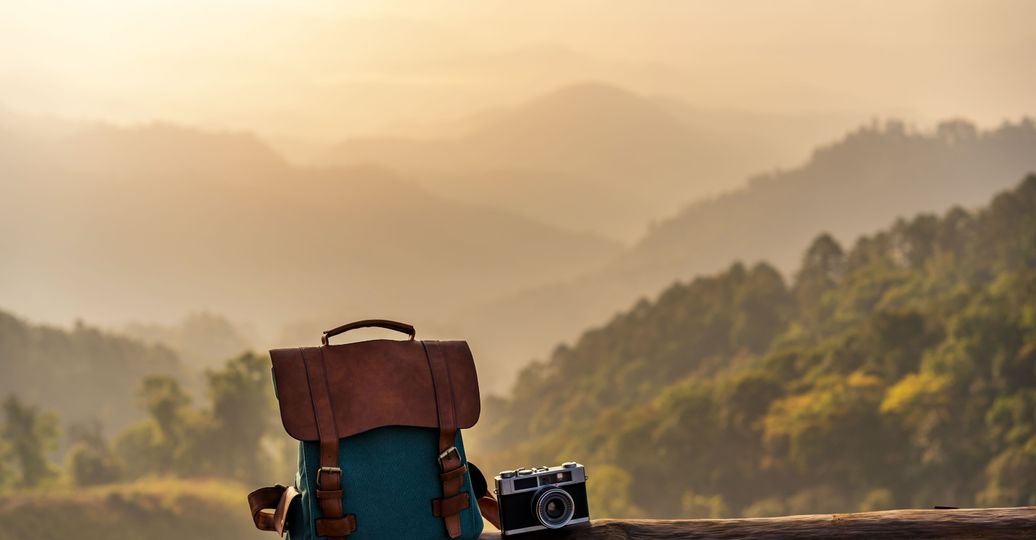 Voyage en Asie – Sac à dos et appareil photo devant un paysage montagneux, évoquant liberté et introspection du voyage solo