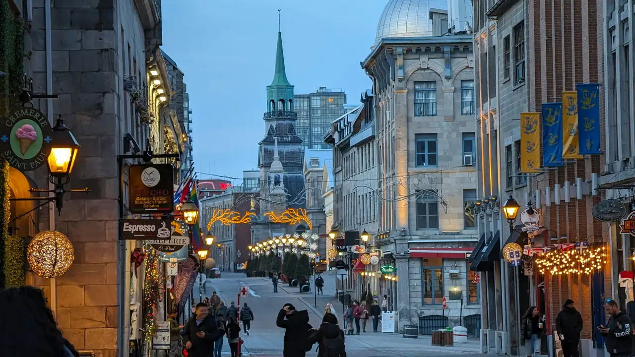 Ruelle historique pavée bordée de bâtiments anciens illuminés avec le clocher de la chapelle Notre-Dame-de-Bon-Secours dans le Vieux-Montréal