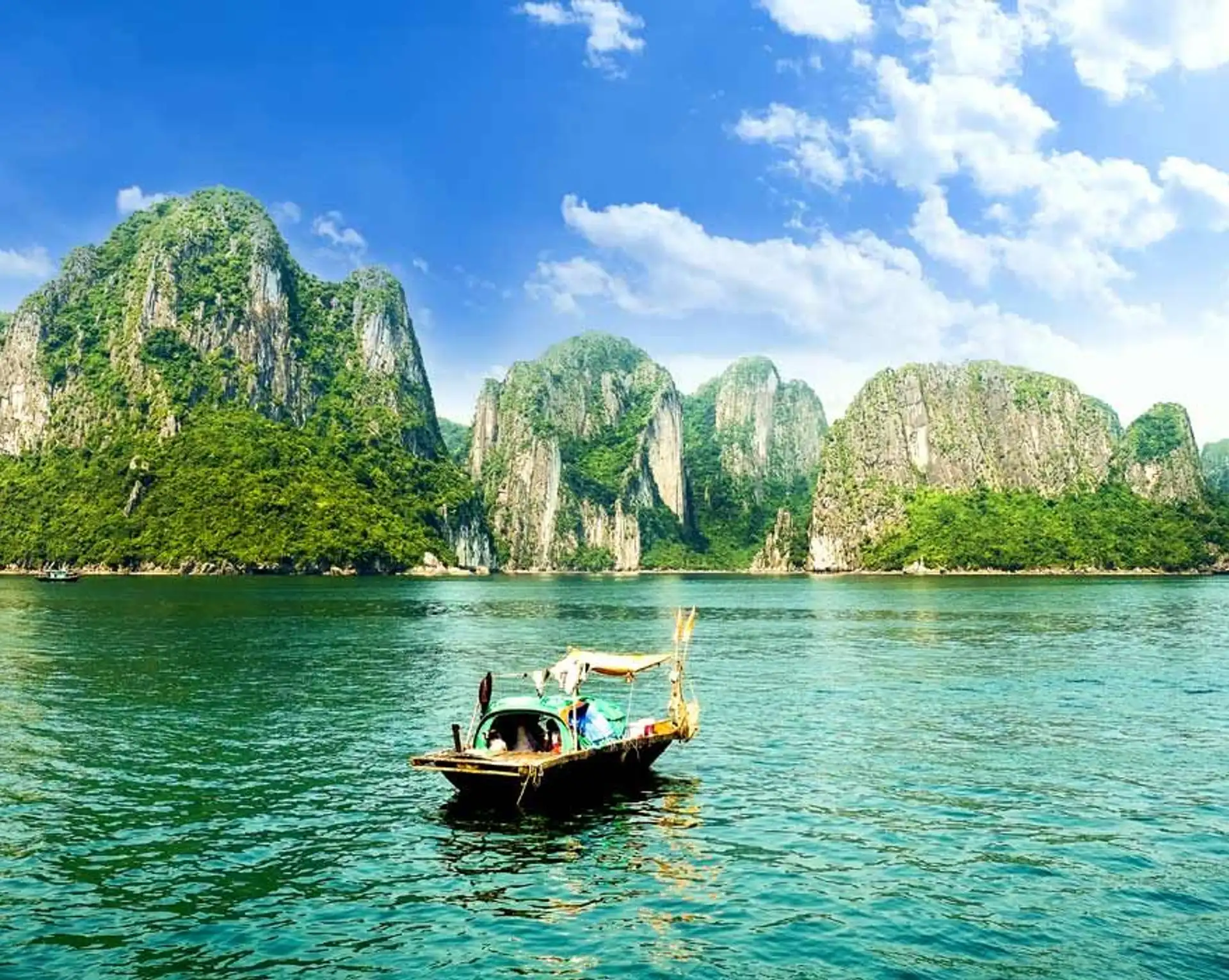 Budget voyage Vietnam 10 jours – Une jonque traditionnelle navigue au milieu des pics karstiques et des eaux émeraude de la baie d'Halong.
