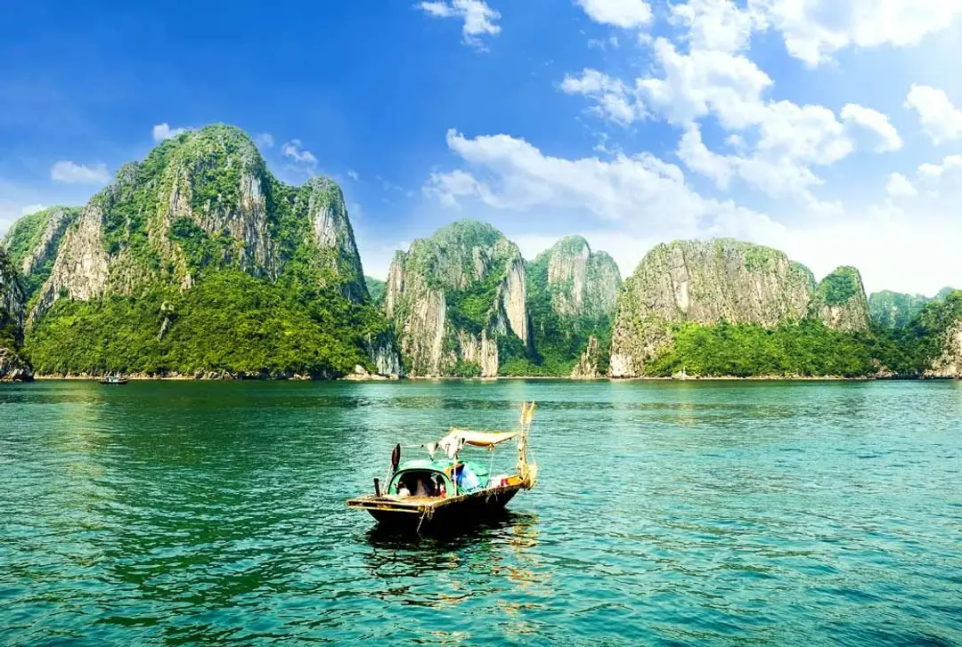 Budget voyage Vietnam 10 jours – Une jonque traditionnelle navigue au milieu des pics karstiques et des eaux émeraude de la baie d'Halong.