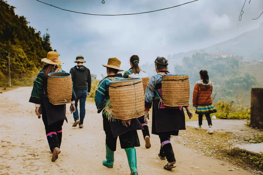 Femmes des minorités ethniques de Sapa portant des paniers en osier traditionnels sur un chemin au Vietnam