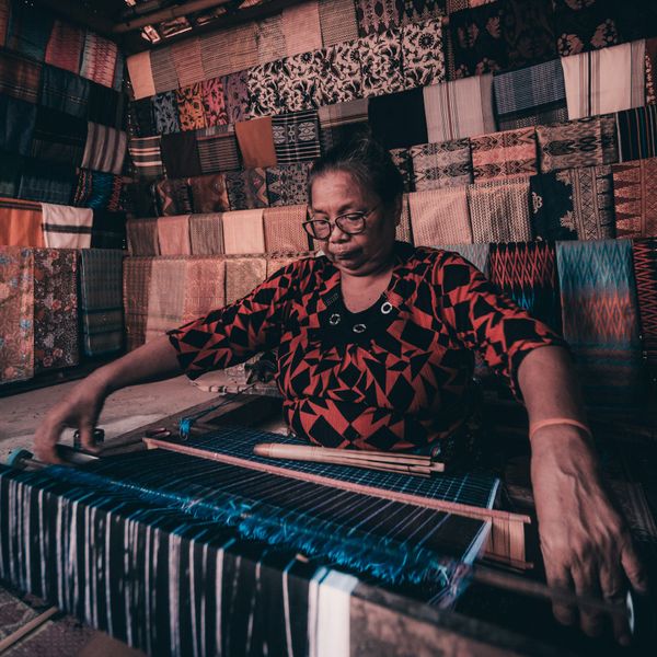 Femme assise tissant dans son atelier.