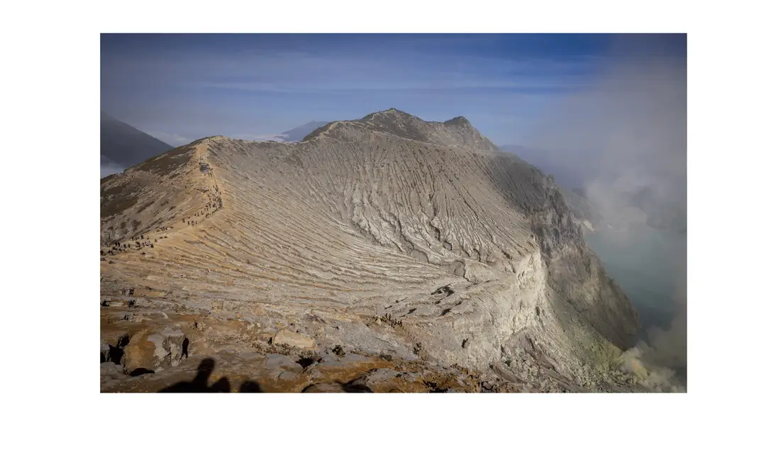Voyage en Indonésie - bord du cratère du Mont Ijen à l’aube avec randonneurs sur le sentier