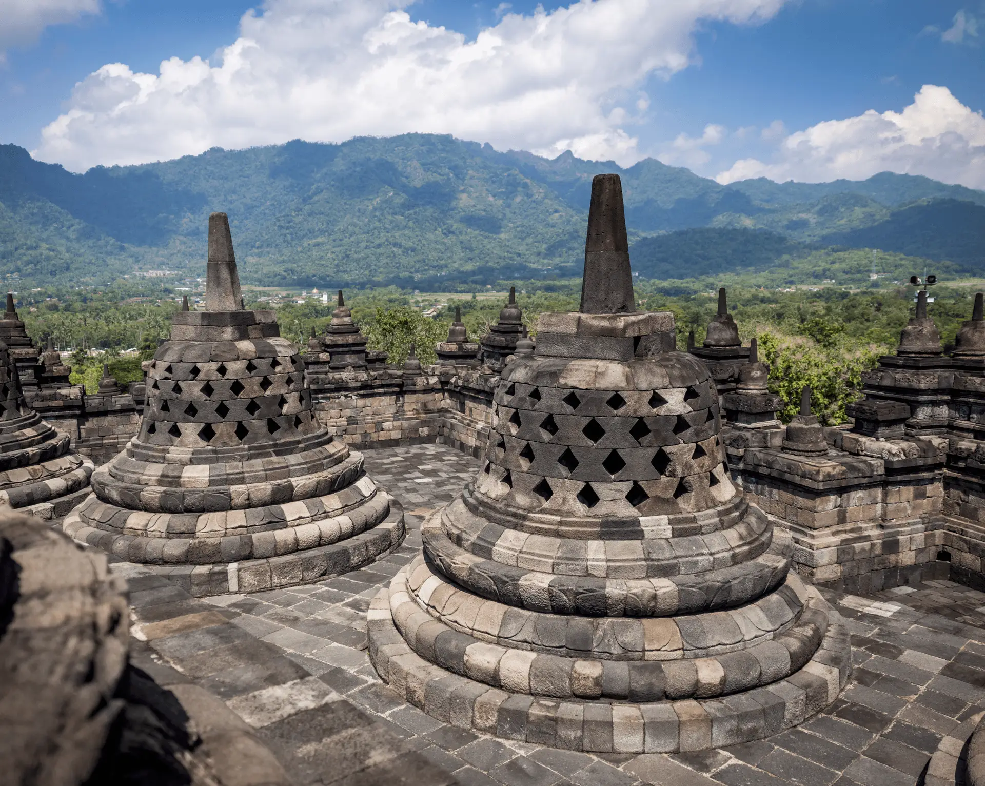 Voyage en Indonésie - stupas perforés au sommet du temple de Borobudur avec les volcans de Java en arrière-plan