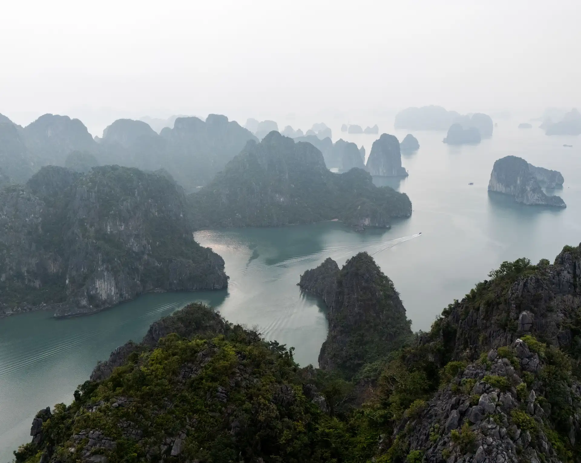 Vue panoramique sur la baie de Bai Tu Long au Vietnam, entre îlots karstiques et eaux émeraude.