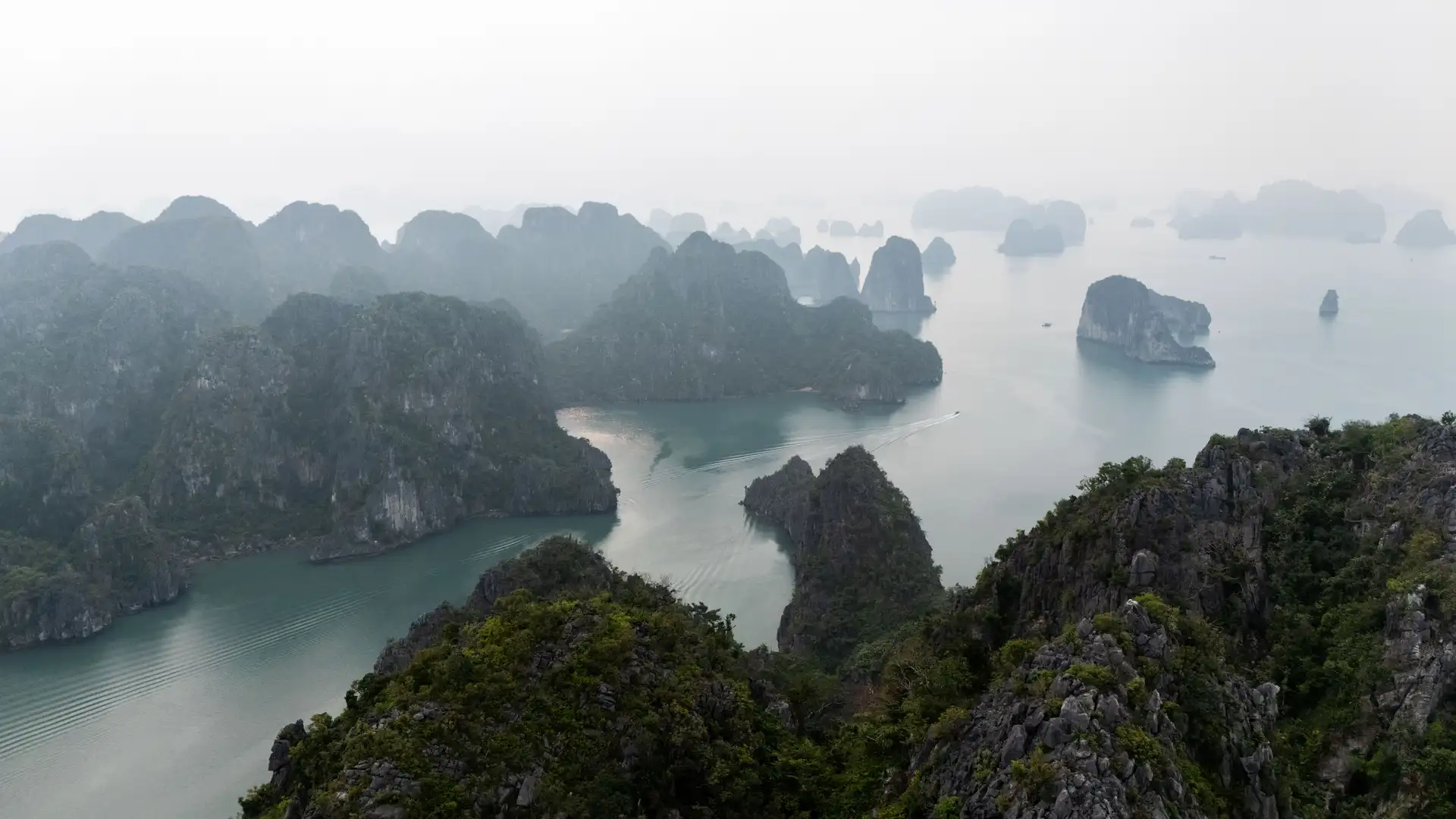 Vue panoramique sur la baie de Bai Tu Long au Vietnam, entre îlots karstiques et eaux émeraude.