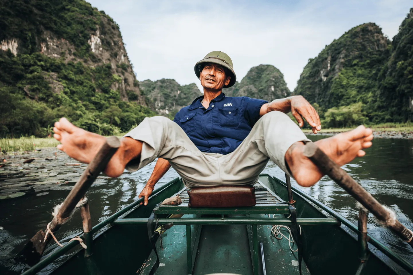 Voyage au Vietnam - sampan traditionnel à Tam Coc avec rameur utilisant la technique ancestrale des pieds