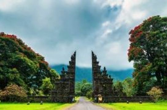 Voyage en Asie — Porte monumentale Candi Bentar à Bali ou Java : architecture sacrée encadrée de végétation tropicale et collines brumeuses.