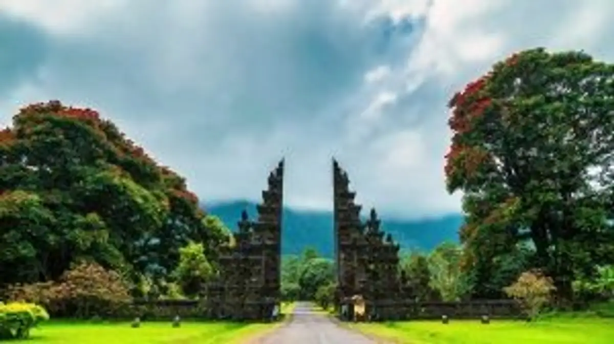 Voyage en Asie — Porte monumentale Candi Bentar à Bali ou Java : architecture sacrée encadrée de végétation tropicale et collines brumeuses.