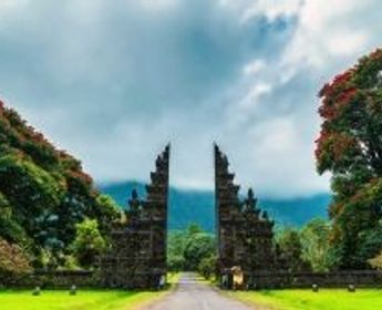 Voyage en Asie — Porte monumentale Candi Bentar à Bali ou Java : architecture sacrée encadrée de végétation tropicale et collines brumeuses.