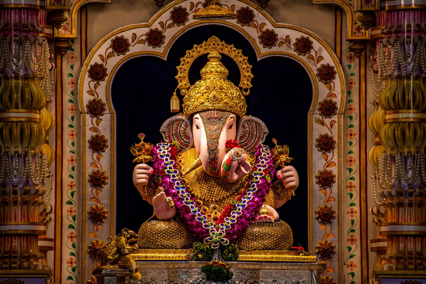 voyage en Inde - Divinité Ganesha ornée de bijoux dorés et de fleurs dans un sanctuaire.