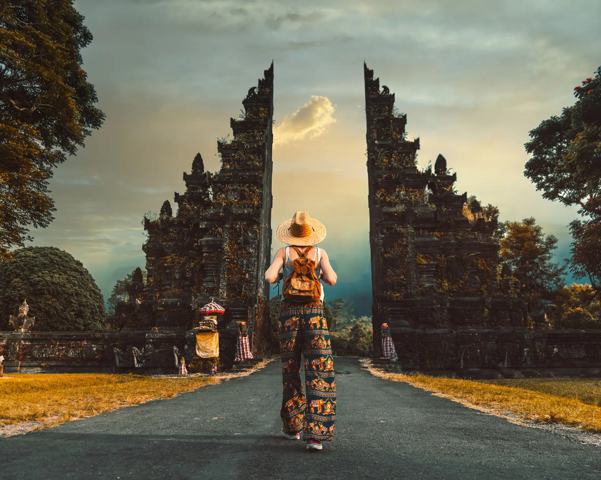 Voyager seul à Bali – Voyageur en solo avec sac à dos marchant vers une porte balinaise traditionnelle Handara Gate.