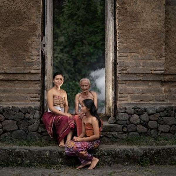 Balinesische Frauen sitzen vor einer Fassade in Bali