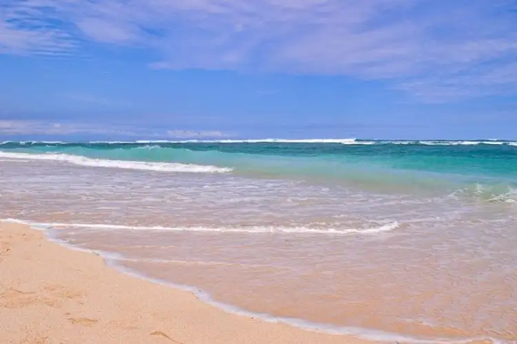 Voyage en Asie — Plage tropicale à Bali : sable clair, eau turquoise et ciel bleu ensoleillé.