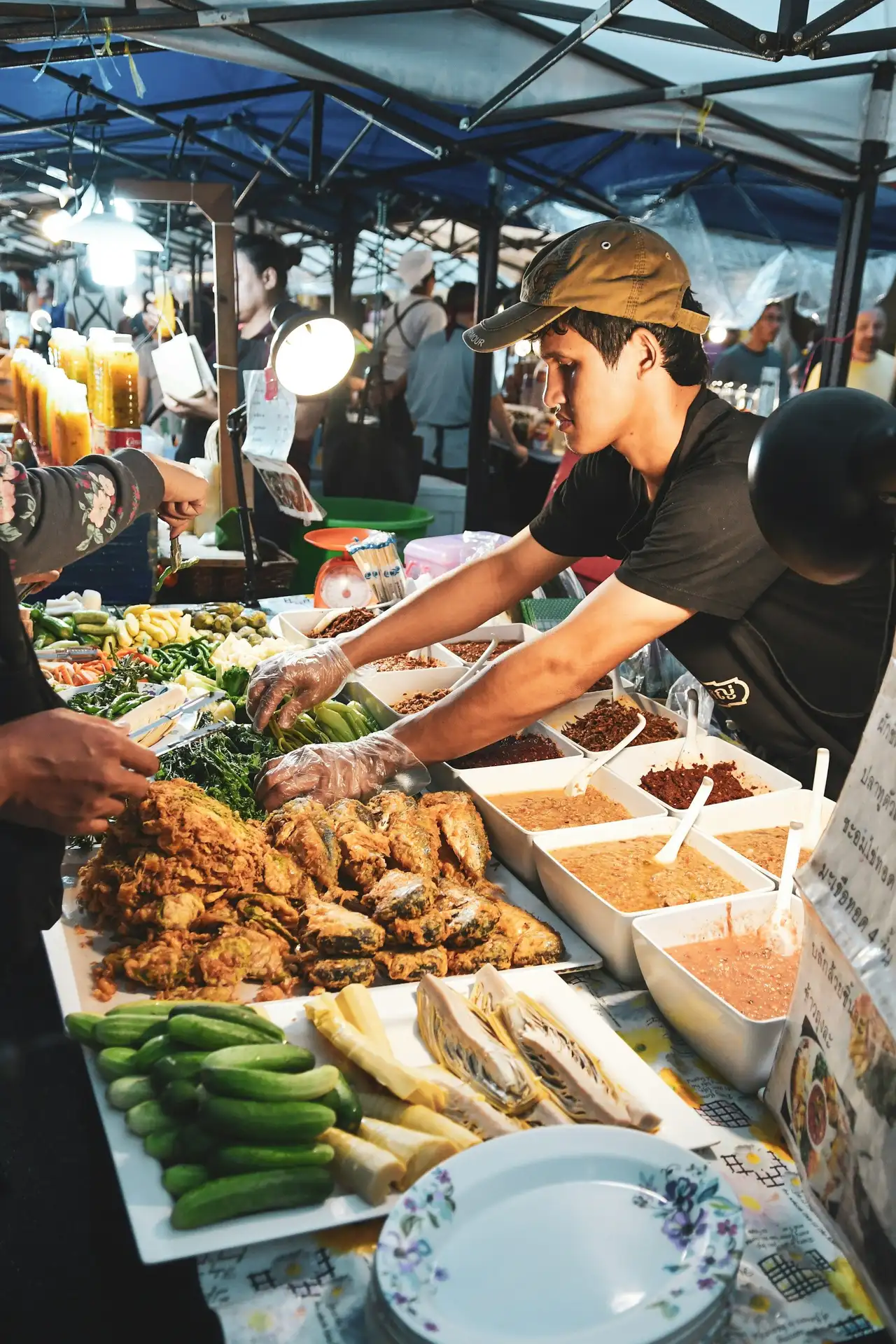 Un stand de street food animé dans un marché de nuit local à Bali, où un cuisinier prépare des plats traditionnels balinais au milieu d'étals de nourriture.