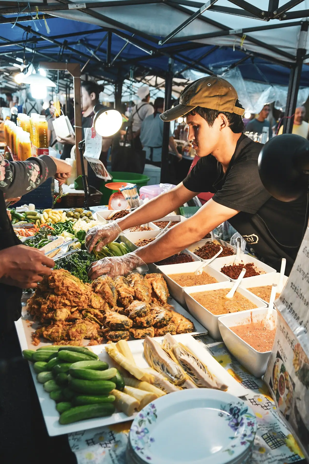 Un stand de street food animé dans un marché de nuit local à Bali, où un cuisinier prépare des plats traditionnels balinais au milieu d'étals de nourriture.