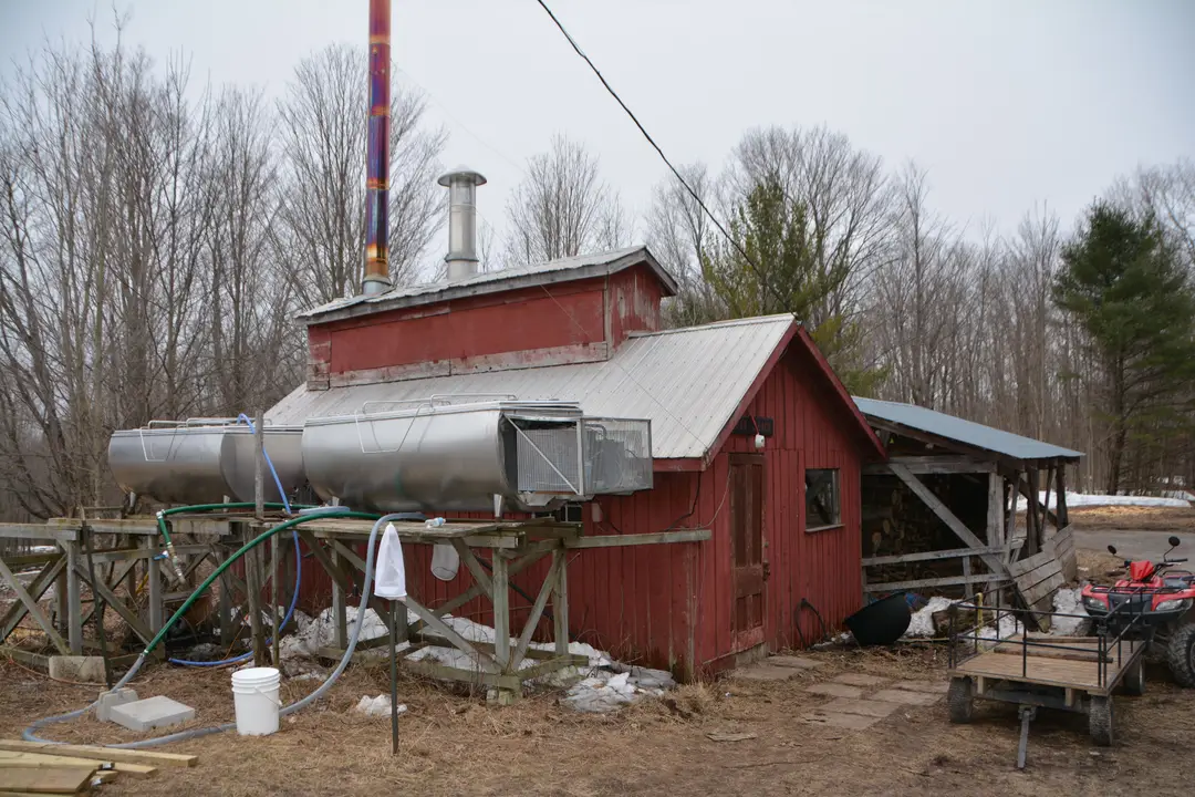 Cabane à sucre rouge traditionnelle à la campagne avec son équipement de production du sirop d’érable