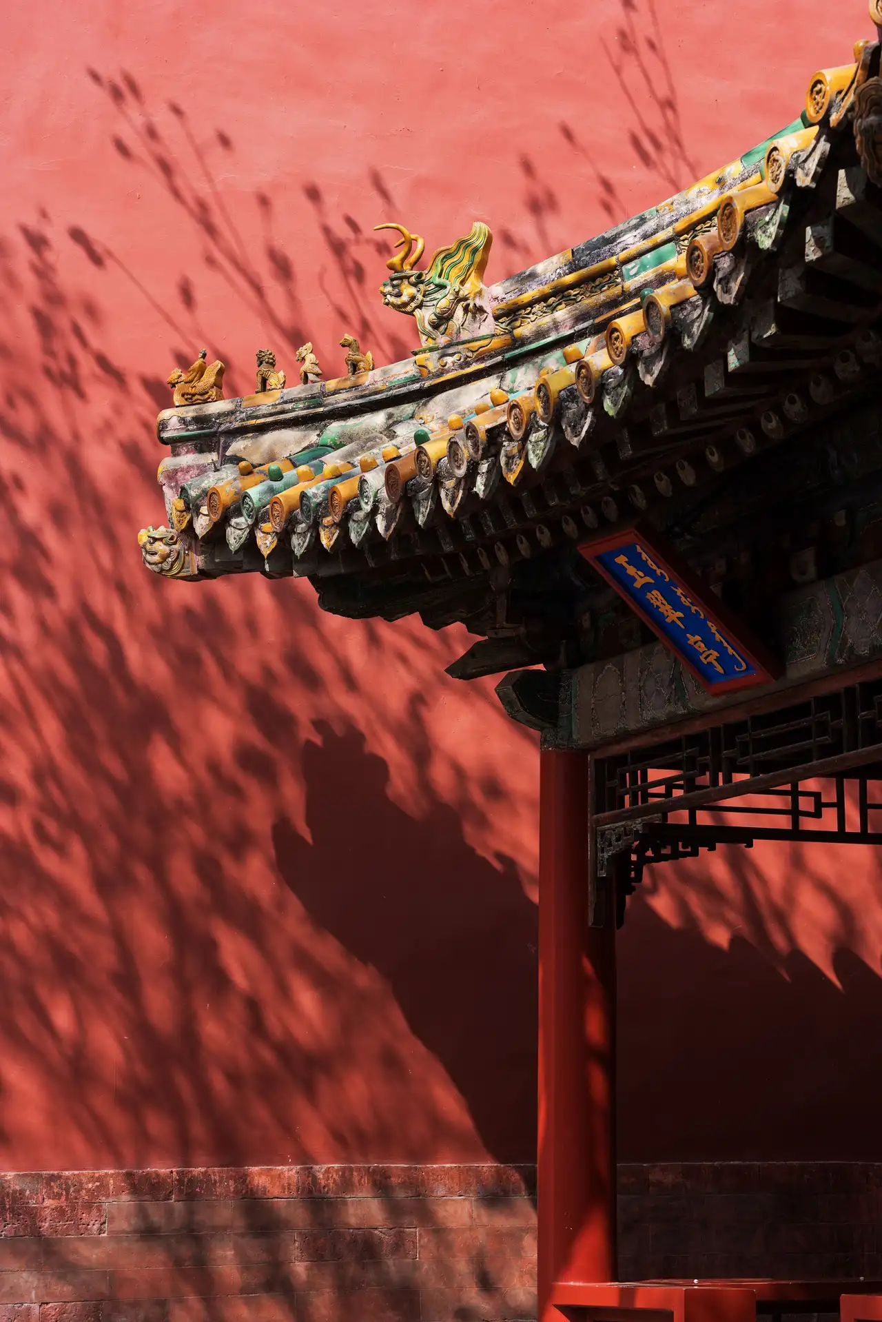 Voyage en Chine – Détail d'un toit impérial aux tuiles vernissées et mur rouge de la Cité interdite à Pékin.