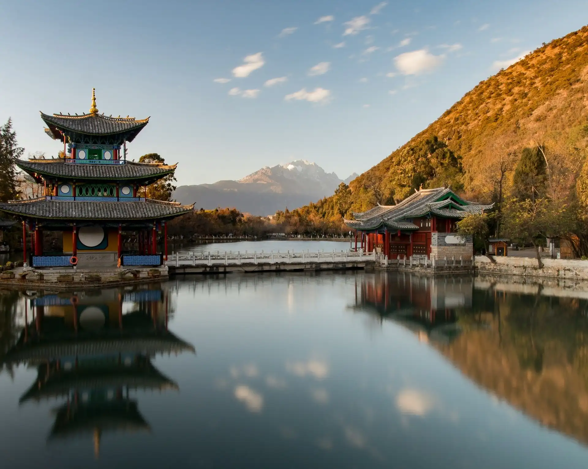 pagode traditionnelle chinoise se refletant sur un etang paisible face a une colline boisee a l automne sous un ciel degage